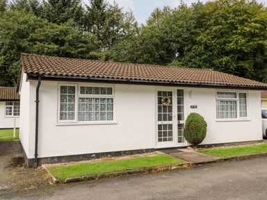 A single story house with tiled roof and windows with patterned curtains at Brook Haven Rosecraddoc Lodge near Liskeard Cornwall