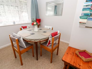 A dining area with a round table covered by a polka dot tablecloth and four wooden chairs with cushions at Brook Haven Rosecraddoc Lodge near Liskeard Cornwall