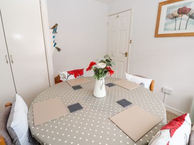 A dining room with a round table covered by a polka dot tablecloth and set with placemats and coasters at Brook Haven Rosecraddoc Lodge near Liskeard Cornwall