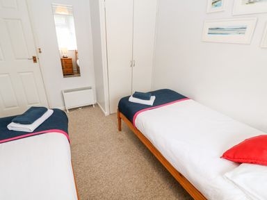 A bedroom with two single beds white bedding and blue blankets with towels on top and a red cushion on one bed at Brook Haven Rosecraddoc Lodge near Liskeard Cornwall