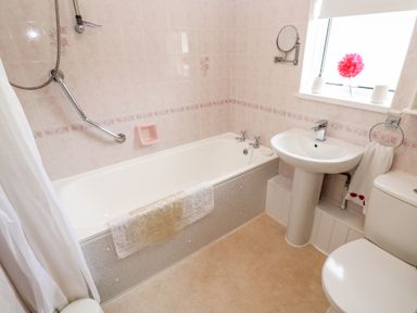 A bathroom with a bathtub sink toilet towel and a window with a flower at Brook Haven Rosecraddoc Lodge near Liskeard Cornwall