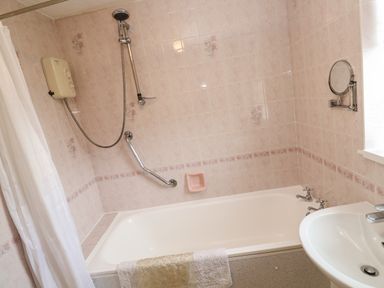 A bathroom with a bathtub shower curtain handrail and sink at Brook Haven Rosecraddoc Lodge near Liskeard Cornwall