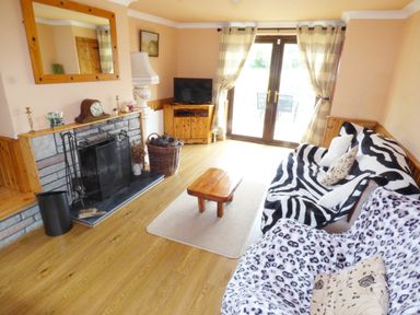 A living room with a stone fireplace a wooden coffee table and two sofas covered with animal print throws at Cookies Cottage Ballyshannon County Donegal