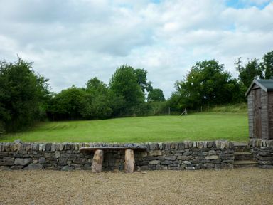 A garden with a stone wall bench gravel area and a wooden shed at Cookies Cottage in Ballyshannon County Donegal