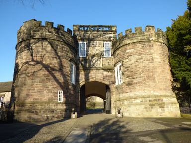 A stone gatehouse with twin round towers and an arched entrance at Crane Field Laithe in Otterburn North Yorkshire