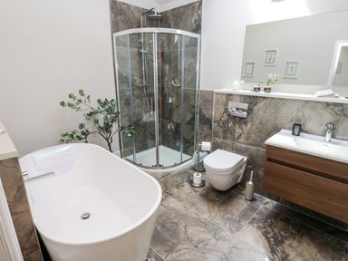 A bathroom with a bathtub, shower, sink, and toilet at Crane Field Laithe, Otterburn, North Yorkshire