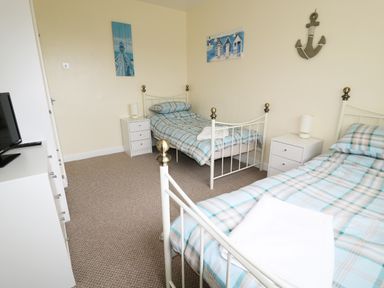 A bedroom with two single beds blue plaid bedding and white nightstands at Anneddle in Four Mile Bridge