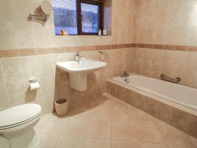 A bathroom with a toilet, a sink, and a bathtub under a window at Hill Bank in Hutton Roof