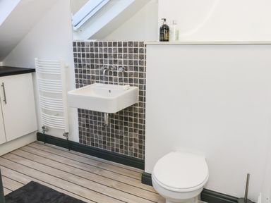 A bathroom with a floating sink and a toilet next to a tiled backsplash at Hill Bank in Hutton Roof