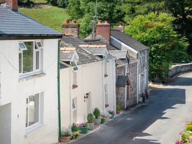 A row of houses along a street with flower pots and greenery at 3 Horse Pool Road in Laugharne