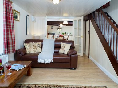 A living room with a brown leather sofa and cat-themed cushions at 3 Horse Pool Road in Laugharne