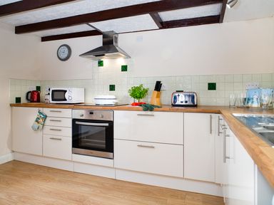 A kitchen with white cabinets wooden countertops microwave toaster and oven at 3 Horse Pool Road in Laugharne