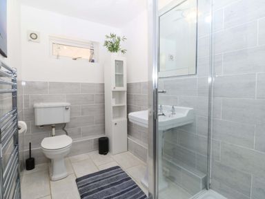 A bathroom featuring a shower, sink, and toilet at Beach House (Ty Traeth) Deganwy