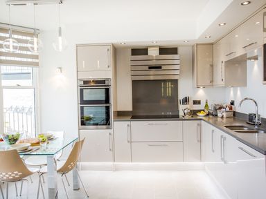 A kitchen with a glass dining table and chairs and modern cabinets at No 6 Arlington Villas in Ilfracombe