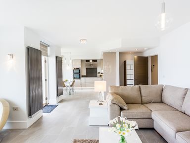 An open-plan living room and kitchen with a beige sofa and a dining table at No 6 Arlington Villas in Ilfracombe