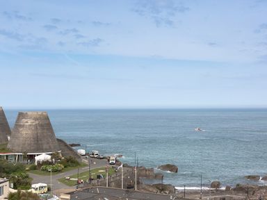 A coastal view with large concrete sea defenses a road with vehicles and people a boat on the water at No 6 Arlington Villas in Ilfracombe