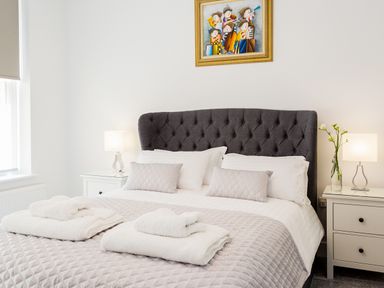 A bedroom with a dark grey upholstered bed headboard and white bedding at No 6 Arlington Villas in Ilfracombe