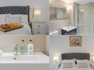 A bedroom with a grey upholstered headboard bedside tables and a tray of food a bathroom with a sink mirror toilet and shower at No 6 Arlington Villas Ilfracombe