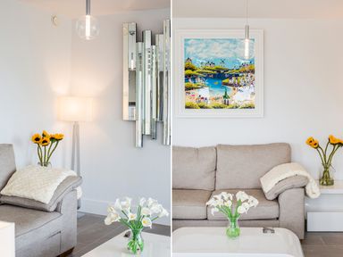 A living room with a beige sofa white table flowers a floor lamp a mirror and a painting at No 6 Arlington Villas in Ilfracombe