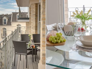 A balcony with a table and chairs next to a dining table set with plates and food at No 6 Arlington Villas in Ilfracombe