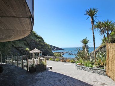 An outdoor patio area with stone pavement plants and a gazebo overlooking the sea at No 6 Arlington Villas in Ilfracombe