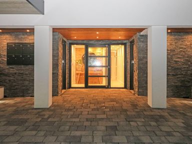 An entrance area with glass doors stone walls and tiled floor at Little Fistral in Fistral