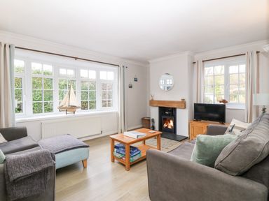 A living room with sofas a coffee table a fireplace and large windows at Glan Dwr in Red Wharf Bay