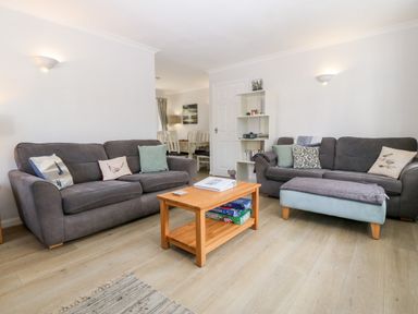 A living room with gray sofas a wooden coffee table and a small bookshelf at Glan Dwr in Red Wharf Bay