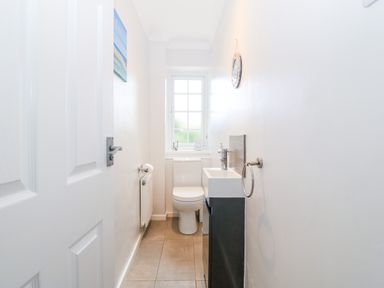 A small bathroom with a toilet a sink a wall mirror and a window at Glan Dwr in Red Wharf Bay