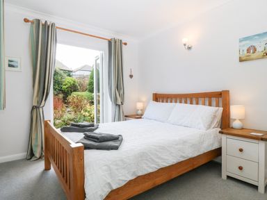 A bedroom with a wooden bed white bedding and bedside tables with lamps at Glan Dwr in Red Wharf Bay