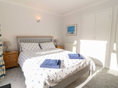 A bedroom with a double bed two bedside tables with lamps a framed picture and a built-in wardrobe at Glan Dwr in Red Wharf Bay