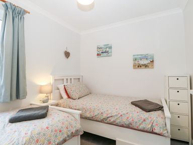 A bedroom with two single beds bedside table with lamp and small drawers at Glan Dwr in Red Wharf Bay
