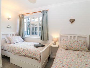 A bedroom with two single beds and a window with curtains at Glan Dwr in Red Wharf Bay