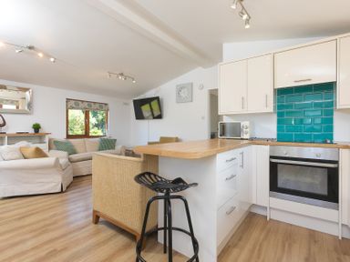 A living room with kitchen area and seating at Costentyn, Tor Down Quarry in St Breward