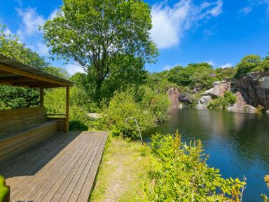 An outdoor area with a bench near a pond at Costentyn, Tor Down Quarry St Breward