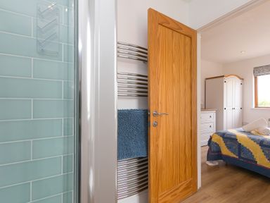 A bathroom area with a towel rail and door opening to a bedroom at Tressa, Tor Down Quarry St Breward