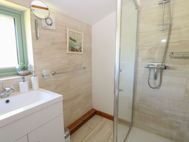 A bathroom with a sink and mirror next to a glass shower enclosure at Lakeside Lodge in East Harling near Thetford