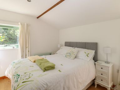 A bedroom with a bed towel and a bedside table with a lamp at Lakeside Lodge in East Harling near Thetford