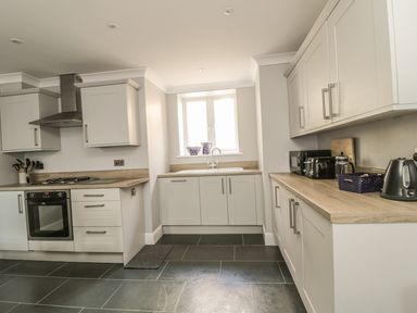 A kitchen with white cabinets black oven and toaster and a window above the sink at Ivy Bank in Windermere
