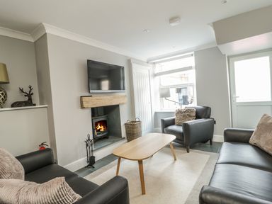 A living room with black leather sofas a wooden coffee table a fireplace and a television at Ivy Bank in Windermere
