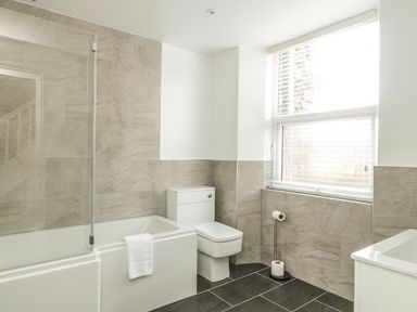 A bathroom with a bathtub shower combination toilet window with blinds and a toilet paper holder at Ivy Bank in Windermere