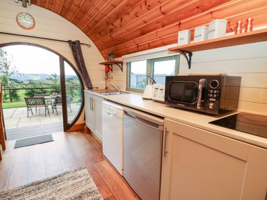 A kitchen with a microwave toaster and sink and outside dining area at Meadow View in Rhayader