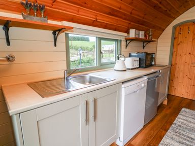 A kitchen countertop with a sink dishwasher kettle toaster and microwave at Meadow View in Rhayader
