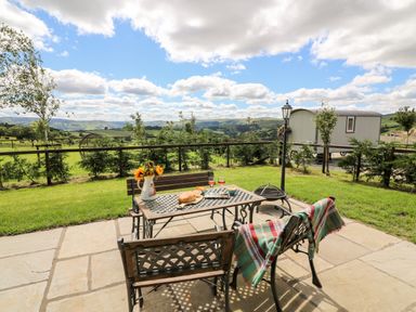 A garden patio with metal table and chairs overlooking fields at Meadow View in Rhayader