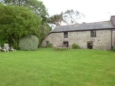 A garden with chairs and a table outside a stone cottage at Old Winery Cottage Golant near Fowey
