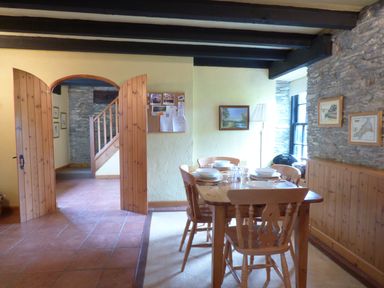 A dining room with a wooden dining table and chairs set for a meal near a window at Old Winery Cottage Golant near Fowey