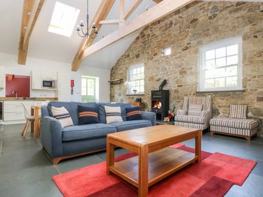 A living room with a blue sofa wooden coffee table fireplace and exposed stone walls at Wheal Grey in Praa Sands