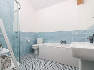 A bathroom with a bathtub toilet sink and corner shower at Wheal Grey in Praa Sands