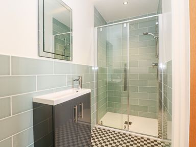 A bathroom with a sink cabinet and a glass shower enclosure at Wheal Grey in Praa Sands
