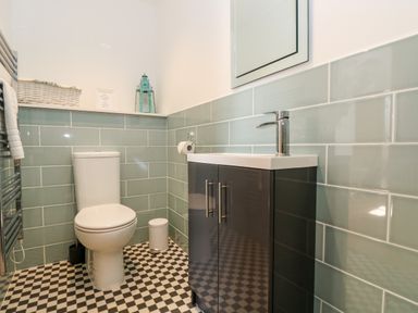 A bathroom with a toilet sink with cabinet mirror towel rail and decorative items at Wheal Grey in Praa Sands
